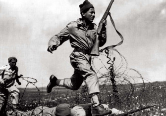 a Haganah fighter dashes across a human bridge formed by two comrades over barbed wire, Tel Aviv, 1948. 